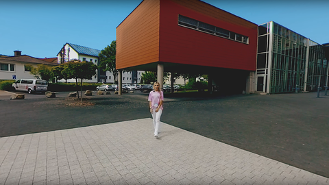 Eine Frau steht auf dem Platz vor dem Haupteingang der Hochschule