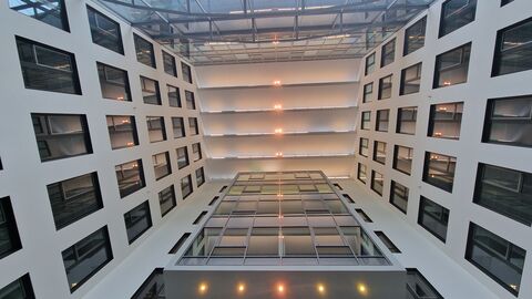 Die Decke des Foyers strahlt durch die Beleuchtung. An den Seiten sind viele Fenster.