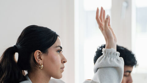 Fragen stellen Eine Anwärterin hebt die Hand, um eine Frage zu stellen.