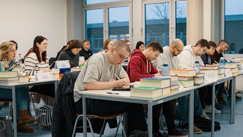 Im Lehrsaal sitzt eine Gruppe in Reihen und lernt