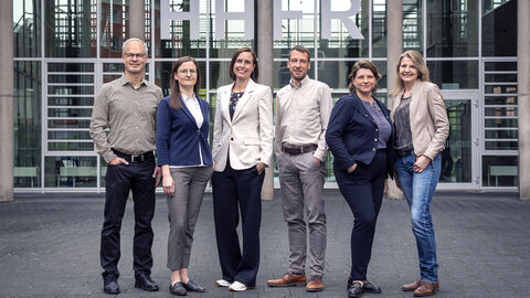 Die Geschäftsbereichsleiterinnen und -leiter stehen vor der Hochschule und schauen in die Kamera.